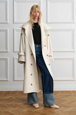 Woman wearing an oversized beige Lyocell trench coat over jeans, front view