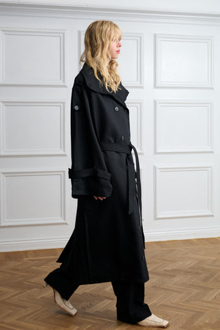 Woman walking in an oversized black Lyocell trench coat, side view