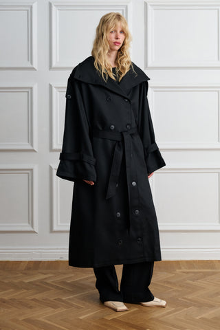 Woman wearing an oversized black Lyocell trench coat, front view