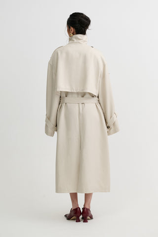 Person wearing a beige trench coat on a white background